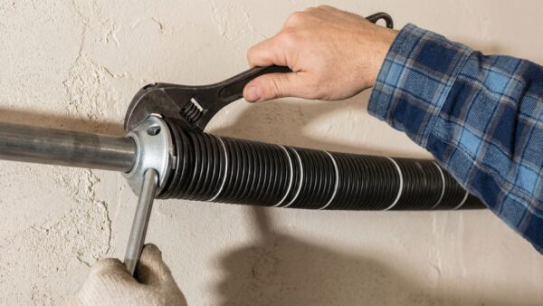 technician adjusting garage door torsion spring with wrench during repair