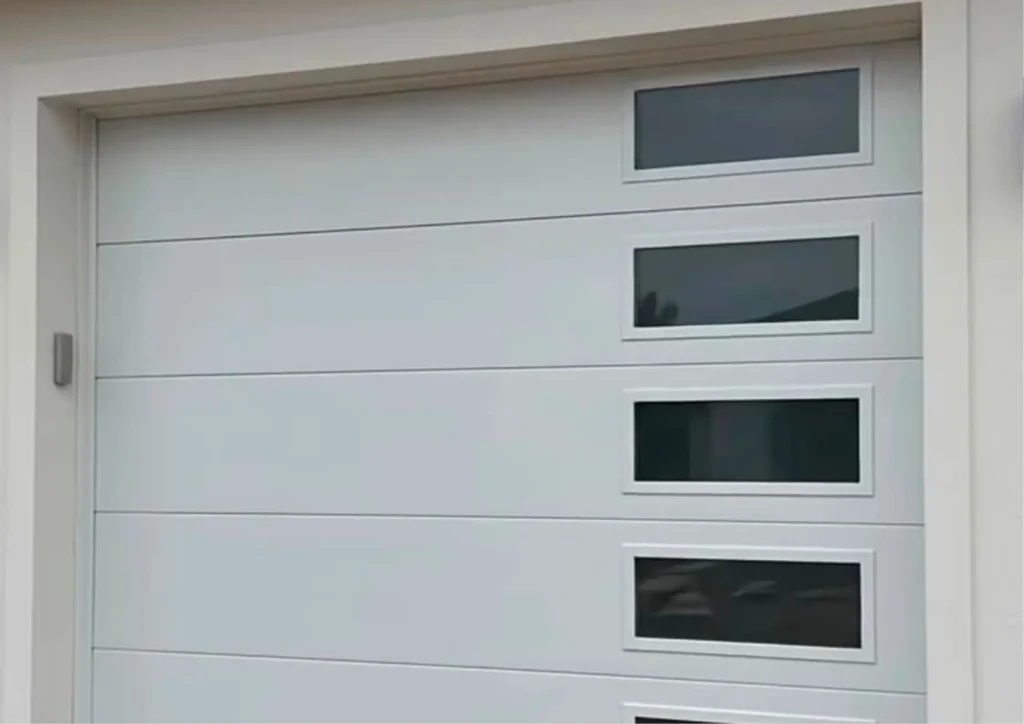 Modern white sectional garage door with window panels on a Merced, CA home