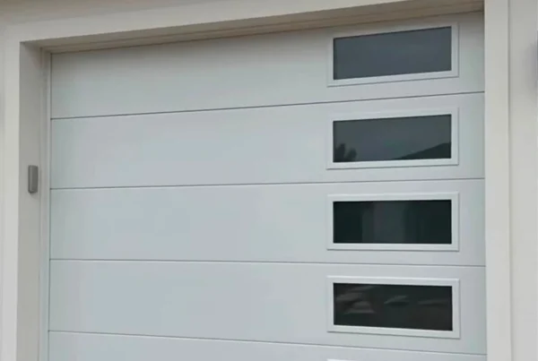 Modern white sectional garage door with window panels on a Merced, CA home