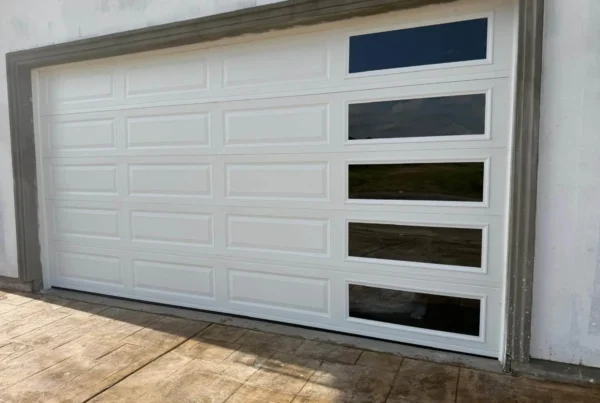 Newly installed white raised-panel garage door with side window panes on a stucco home in Dinuba, CA